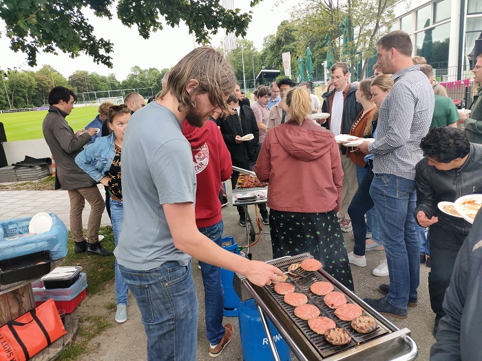 foto van collega die hamburgers grilt op de barbecue